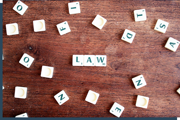 A wooden table with scrabble tiles spelling out the word " law ".